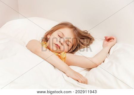 Cute girl sleeping under a blanket in bed in the bedroom. Lying on bed. The concept of awakening and the time of sleep. Portrait of a close-up with an instagram filter.