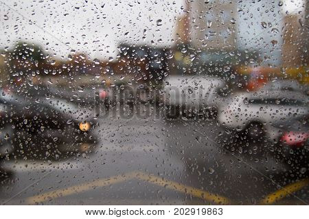 Background of moving rain drops on a window glass in a rainy day. Auto