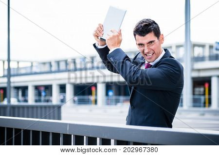 Angry business man destroying his tablet computer, his project has clearly gone wrong