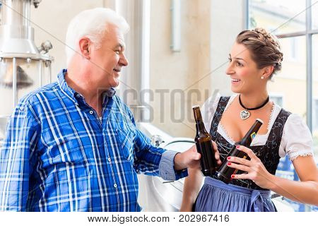 Brewer and woman toasting in beer brewery close to brewhouse