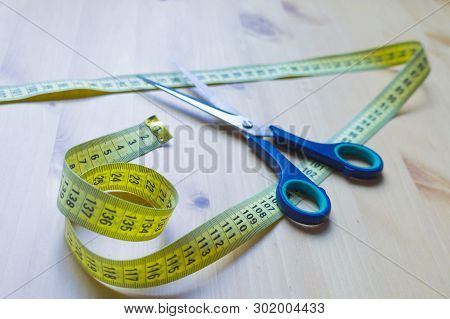Scissors And Centimeter On A Wooden Table
