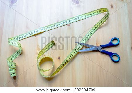 Measuring Tape And Scissors Lying On A Wooden Table