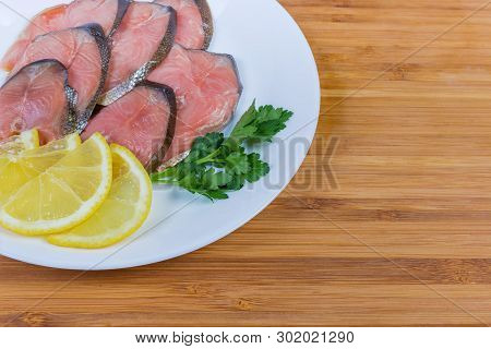 Fragment Of White Dish With Slices Of Smoked Pink Salmon, Lemon Slices And Parsley Twig Close-up On 