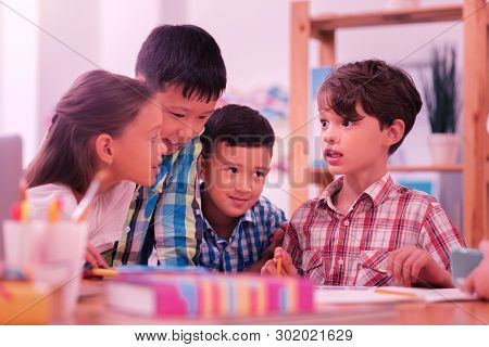 Children At The Schooldesk Discussing Their Exercises.