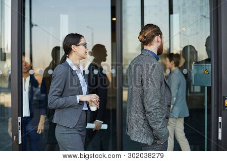 Group Of Modern Business People In Formal Outfits Coming In Convention Center Through Revolving Door