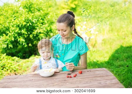 Happy Loving Family. Mother And Her Son Child Boy Are Eating Laered Dessert In Sunny Day In Green Ga
