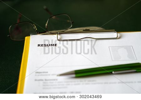 Resume On A Clipboard With Office Table Background. A Hiring Or Employment Concept