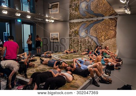 Melbourne, Australia - March 17, 2018: Visitors Resting On The Hand Tufted Wool Rug Entitled Santa C