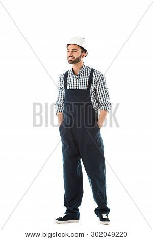 Handsome Smiling Construction Worker With Hands In Pockets Looking Up Isolated On White