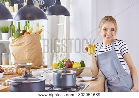 The Girl At The Table In The Kitchen With A Glass Of Orange Jui