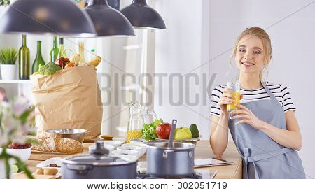 The Girl At The Table In The Kitchen With A Glass Of Orange Jui