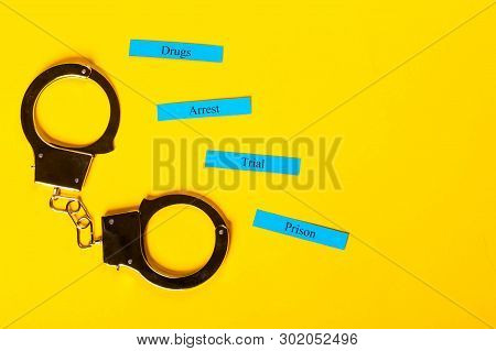 Crime Concept Showing Handcuffs On A Yellow Background With Arrest Tial Prison