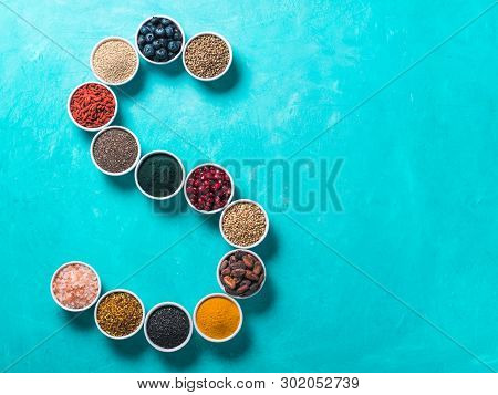 Above View Of Various Superfoods In Smal Bowl In Form S Letter On Blue Background. Superfood As Chia