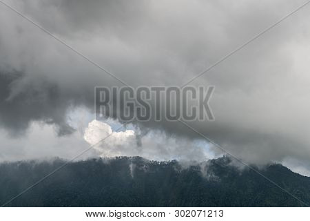Bali, Indonesia - February 25, 2019: Rainy Cloudscape Over Dark Forested Mountains In Bedougoel. Sha