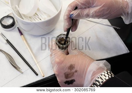Beauty Brows Care Concept: Master Is Mixing Henna For Eyebrows Coloring. Swatches On Hand In Glove