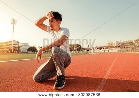 Tired Wet Athletic Man Wiping Sweat His Hand At Sport Stadium With Sunset.