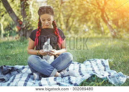 Pretty Asian Girl Hugging Bunny On Summer Nature. Beautiful Dark-haired Girl With Kanekalons In Hair