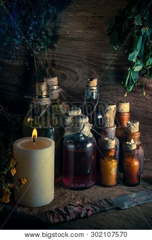 A Witchery Stuff: Multiple Tincture Bottles, Bunches Of Dry Healthy Herbs, Stack Of Ancient Ritual T