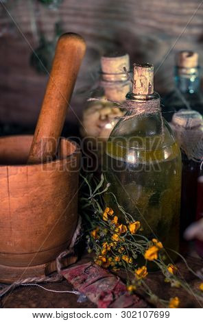 A Witchery Stuff: Multiple Tincture Bottles, Bunches Of Dry Healthy Herbs, Stack Of Ancient Ritual B