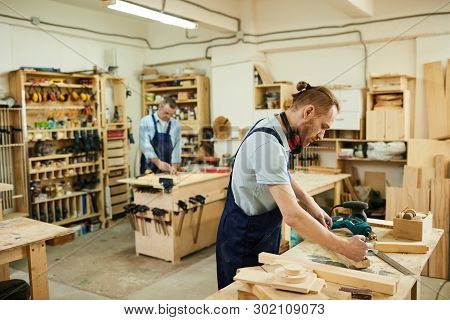 Side View Portrait Of Two Carpenters Working With Wood Standing At Tables In Workshop, Copy Space