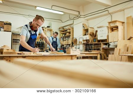 Wide Angle Portrait Of Two Carpenters Working With Wood Standing At Tables In Workshop, Copy Space