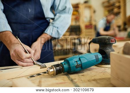 Closeup Of Mature Carpenter Working With Wood Standing At Table In Workshop, Copy Space