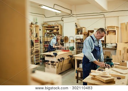 Carpenters Workshop With Two People Assembling Wooden Furniture At Workstations, Copy Space