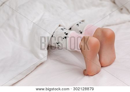 Pair Of Kid Bare Feet In Bed On White Sheets