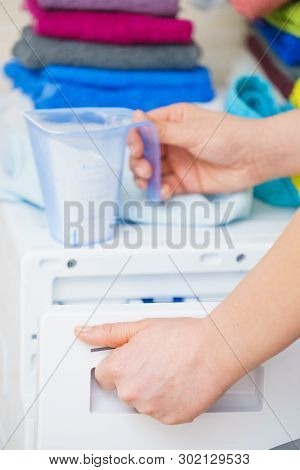 Washing Powder Detergent And Measuring Cup Pouring Into Machine. Household Duties, Clothes Laundry O