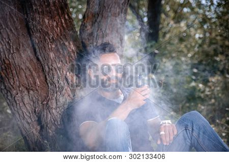 Modern Smoker Enjoying An E-cigarette In The Fresh Air. Smoking Cessation Tobacco.