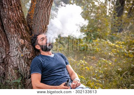 Bearded Man Exhaling Vapor From Electronic Cigarette. Health Concept.