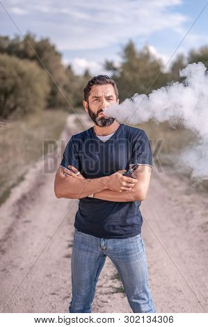 Modern Smoker Vaping An Electronic Cigarette In The Woods. Smoking Cessation Tobacco.