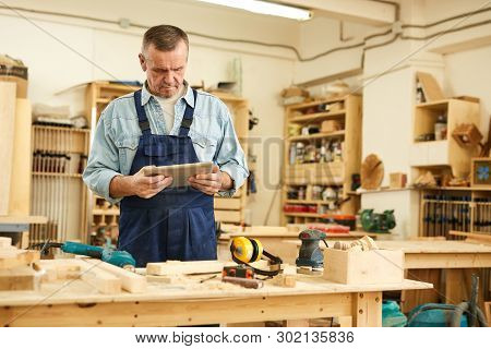 Waist Up Portrait Of Senior Carpenter Using Tablet While Working In Joinery, Copy Space