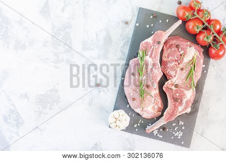 Copy Space On Gray Stone Background. Two Steaks Of Meat With Pepper, Garlic And Rosemary. Slices Of 