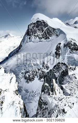 Snow-capped Alpine Peaks In Switzerland. Rocks And Stones Under Snow And Glaciers In Quiet, Calm Wea