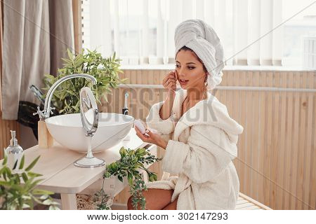 Attravtive Girl Uses Sponge For Own Makeup In The Morning At Bathroom. Beauty Concept.