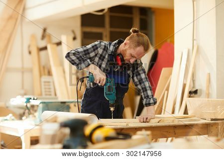 Waist Up Portrait Of Modern Carpenter Drilling Wood While Working In Joinery Lit By Sunlight, Copy S