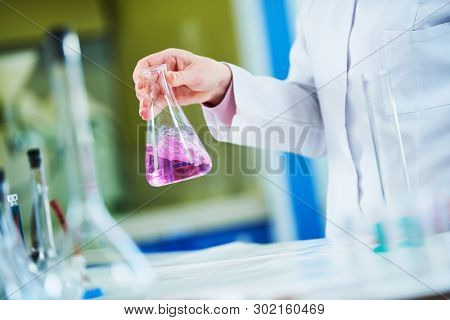 Chemical laboratory. Hand with flask with solution