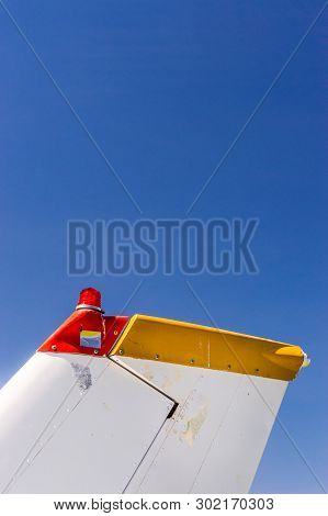 Tail Fin, Rudder And Beacon Lights, Small Single Engine Airplane With Old Paint And Bright Blue Sky.