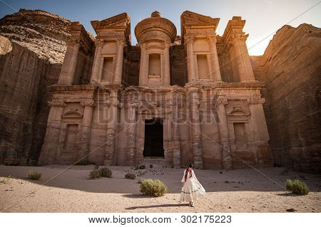 Asian Woman Tourist In White Dress Standing At Ad Deir Or El Deir, The Monument Carved Out Of Rock I
