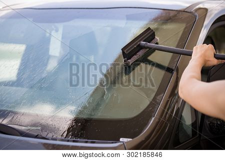 Hands Of The Girl Wash The Windshield Of The Car With A Special Brush From Dried Flying Insects. The