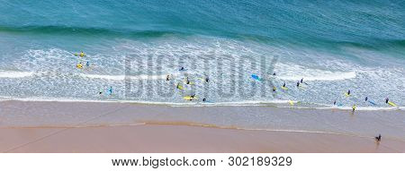 Surfers In The Waves Off Mawgan Porth Beach, Cornwall, Uk