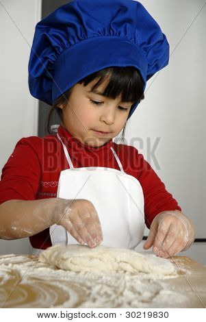 Bambina cucinare una pizza in una cucina.Ragazzino in una cucina.