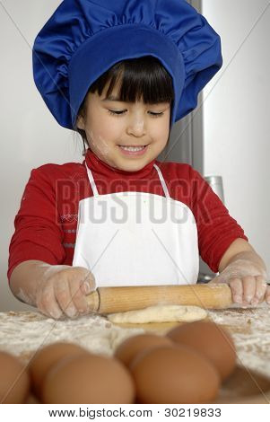 Bambina cucinare una pizza in una cucina.Ragazzino in una cucina.
