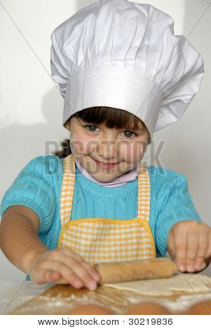Bambina cucinare una pizza in una cucina.Ragazzino in una cucina.