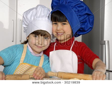 Due bambine cucinare una pizza in una cucina.Ragazzino in una cucina insieme.