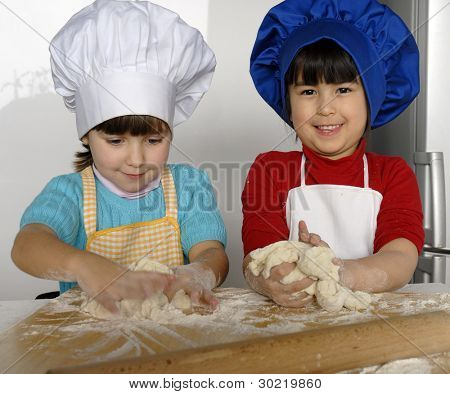 Due bambine cucinare una pizza in una cucina.Ragazzino in una cucina insieme.