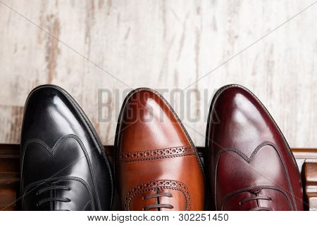 Black and brown full grain leather shoes on wooden display in in men shoes boutique store.
