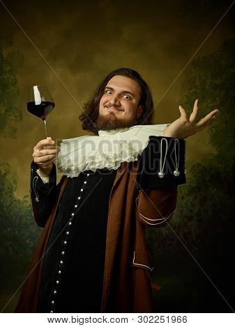 Young Man As A Medieval Knight On Dark Studio Background. Portrait Of Male Model In Retro Costume. H