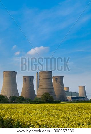 Portrait Shot Of Cooling Towers Of A Coal Fuelled Power Station In The Foreground Is A Bright Yellow